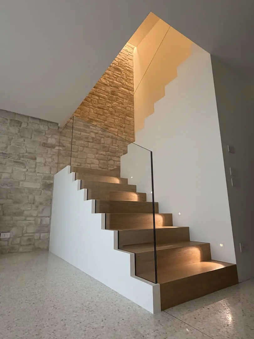 Scala di design in legno e vetro illuminata.